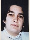 Gloria Edinburg-George: A woman with short dark hair and a white turtleneck shirt looks at the camera with a neutral expression.
