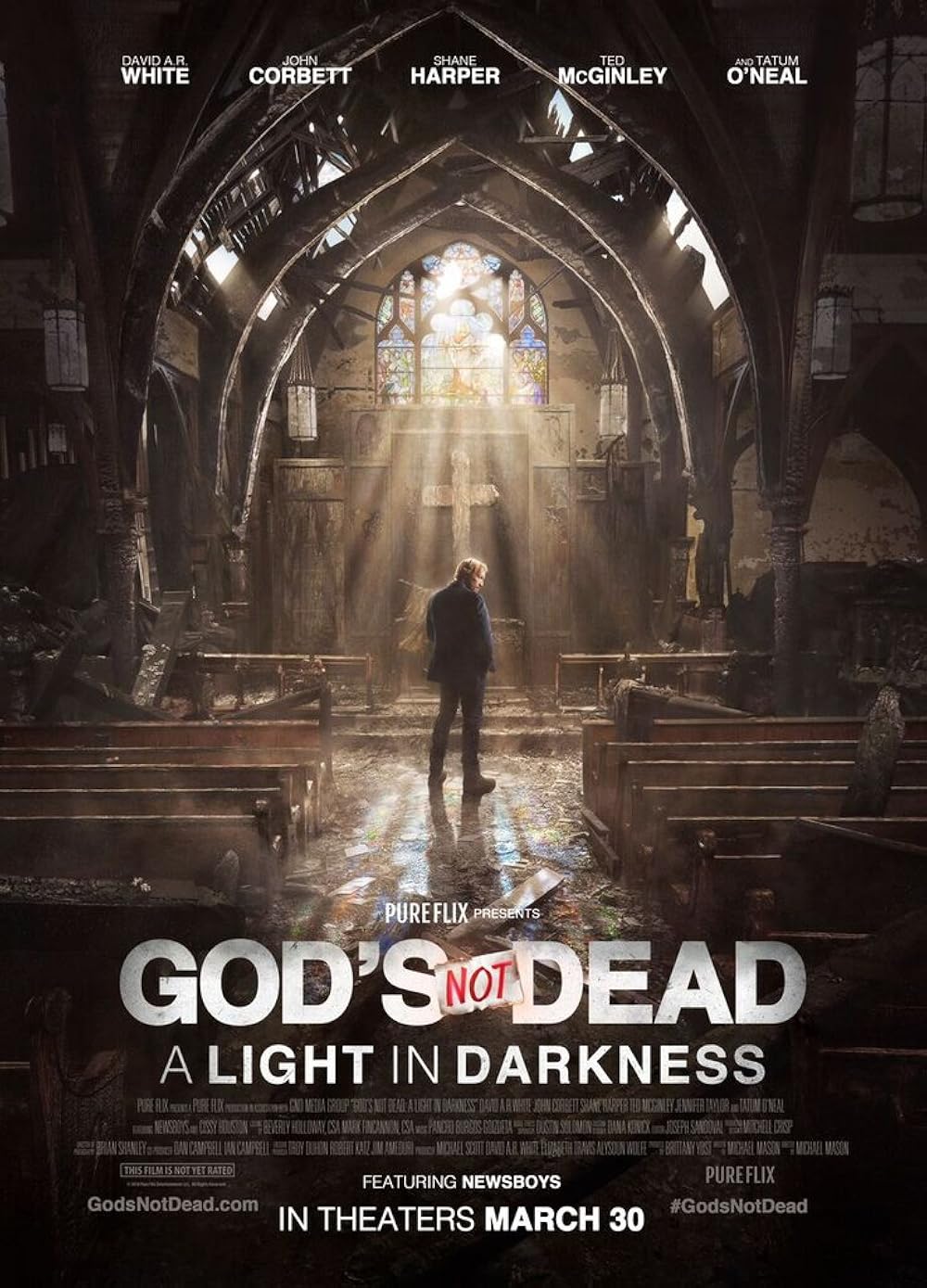 a man stands alone in the center aisle of a damaged, sunlit church with broken pews and debris, featured in the "god's not dead: a light in darkness" movie poster.