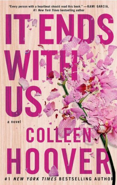 Book cover of "It Ends With Us" by Colleen Hoover, featuring bold pink text over a wooden background with shattered pink flowers.