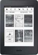 A Kindle e-reader displays a grid of six book covers on its screen, including titles by Jodi Picoult and Stephen King.